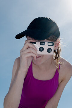Young man takes photo with disposable camera under sunny sky