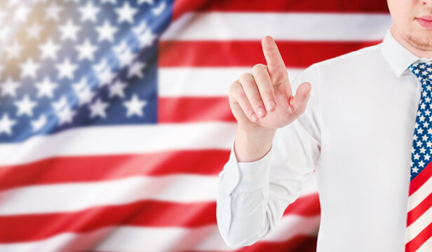 Man in a patriotic necktie points before a waving American flag