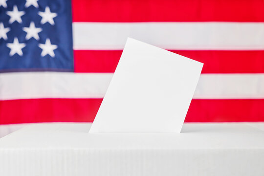 Blank ballot standing in a voting box before an American flag