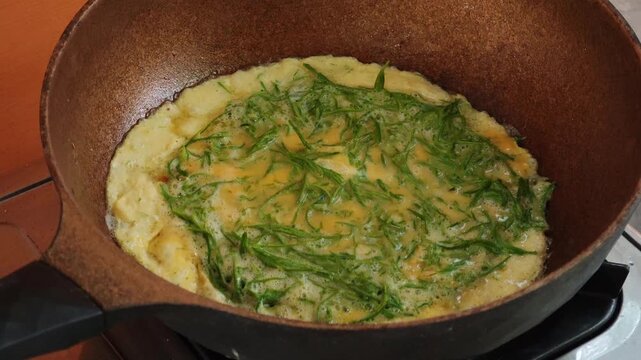 Cooking a Cha-om omelet in a pan