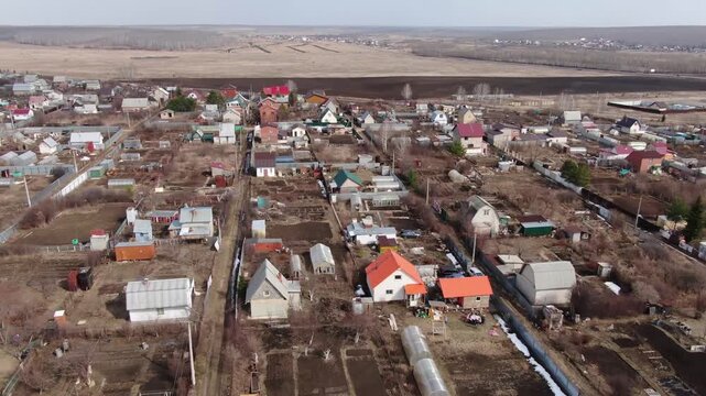 Aerial view of a quiet village nestled in a dry landscape. Houses cluster together, rooftops in varied hues. , so no emotions to convey. Good for showcasing rural life or quiet countryside scenes