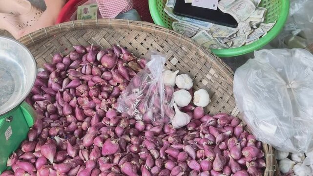 Customer putting garlic next to a bag of shallots while vendor checking paper money at a traditional market in central vietnam