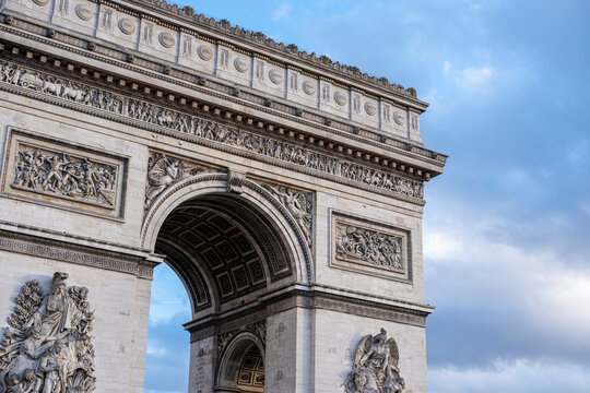 Arc de Triomphe in Paris France rises against a blue sky with sculpted stone details and classical architecture highlighted by clear daylight