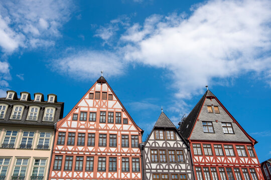 Historic half-timbered houses at R&ouml;merberg in Frankfurt Germany form a colorful row of traditional facades beneath a bright blue sky