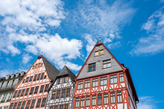 Traditional half-timbered buildings at R&ouml;merberg in Frankfurt Germany show colorful gabled facades and repeating windows under a bright sky