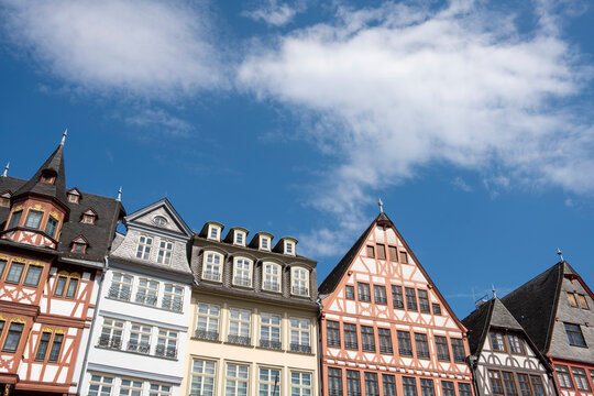 Historic half-timbered buildings at R&ouml;merberg in Frankfurt Germany rise beneath a blue sky with clouds in a colorful architectural cityscape