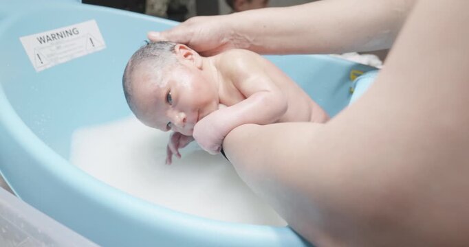 mom bathing her baby. mom giving her newborn their first bath. baby's bath. newborn in the water