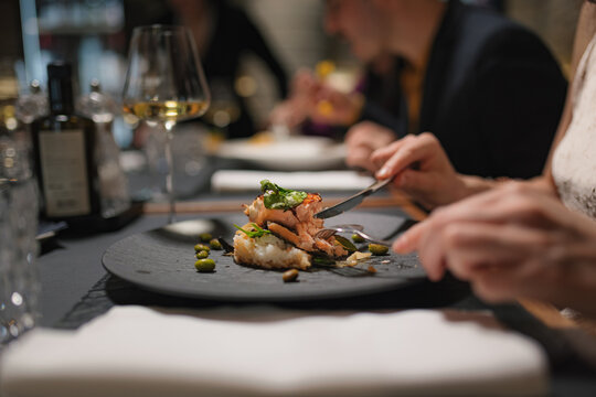 Group of friends dine together in upscale restaurant enjoying their meal and drinks.