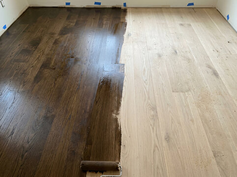 Hardwood floor staining before and after | Applying dark wood stain to light oak planks | Professional floor refinishing and restoration process | Interior home renovation and flooring upgrade