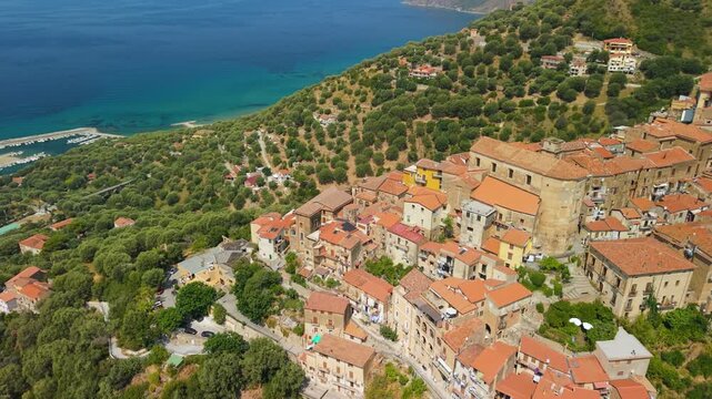 Pisciotta Cilento Campania Italy aerial drone dynamic rotation emerald sea green hills orange tile roofs hilltop village coastal mountain scale travel 4k video
