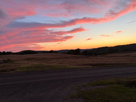 Pink sunset clouds over rural farmland and rolling hills