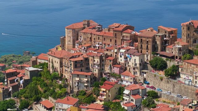 Pisciotta Cilento Campania Italy 70mm drone telephoto hilltop borgo red roofs castle rose morning light sea backdrop passing boats travel destination 4k video