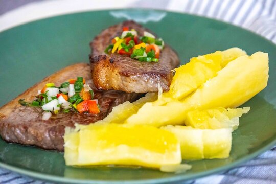 Carne de sol, a traditional northeastern Brazilian dish of salted sun-dried beef served with boiled cassava, fresh onion and bell pepper vinaigrette, chili pepper sauce and acerola juice.