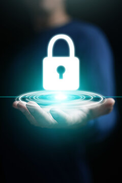 Cybersecurity concept, A man hand holding glowing padlock icon for system, data, or network protection, security, safety, and privacy on vertical dark copy space background for technology concept.