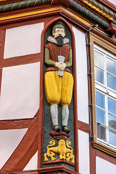 A detail of a half-timbered house featuring a carved figure in period costume and colourful ornamentation; decorative elements on the historic half-timbering of a house in Alsfeld
