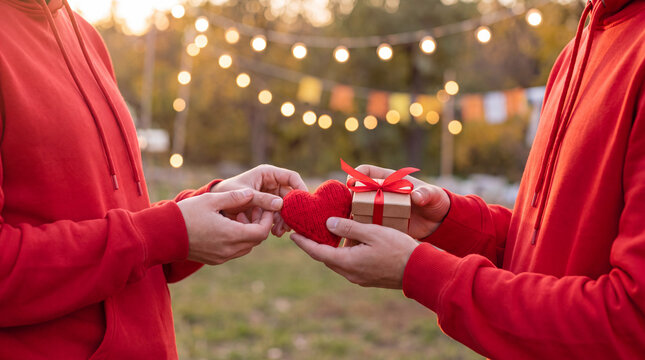 Volunteer hands hold a small red heart and miniature gift box for Giving Tuesday, symbolizing love and generosity in a clean charity campaign.