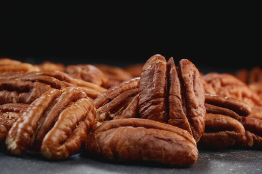 Extreme macro shot of fresh premium pecan nuts with selective focus on dark background with artistic lighting. Perfect for healthy eating, gourmet food, culinary, and dietary content.