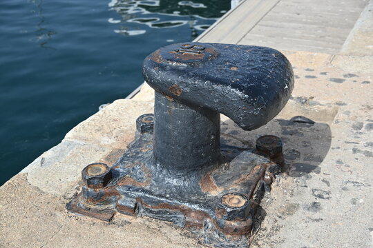 Close Up of a Cast Iron Mooring Bollard in a Harbor with Chairs Nearby