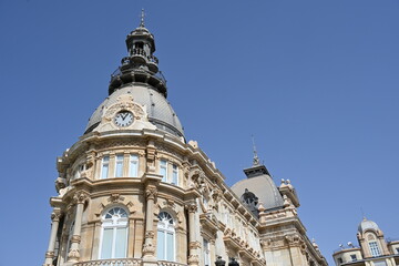 Obraz premium Beautifully Ornate Spanish Townhouse with a Clock Against a Blue Sky