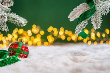 Naklejka premium A Christmas background featuring an abundant array of red and green baubles with golden patterns beneath frosted pine branches, wrapped in ribbon on snow, set against deep green with lights.