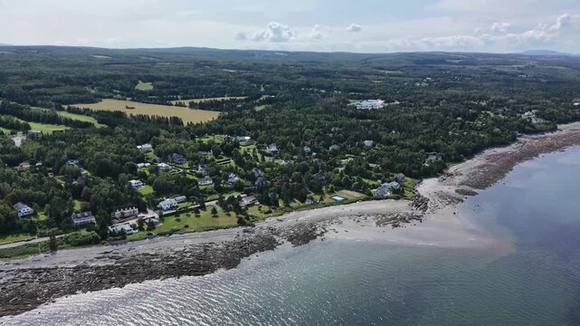 Aerial panorama of M&eacute;tis‑sur‑Mer reveals vibrant green coastal terrain along the St. Lawrence River, highlighting the region&rsquo;s natural beauty and expansive shoreline.