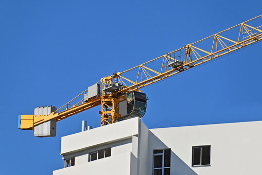 Yellow tower crane and white new building