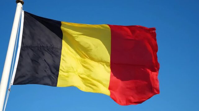 Waving flag of belgium against a clear blue sky