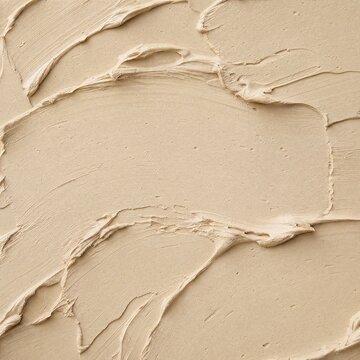 Beige clay mask texture with smeared skincare cream surface  