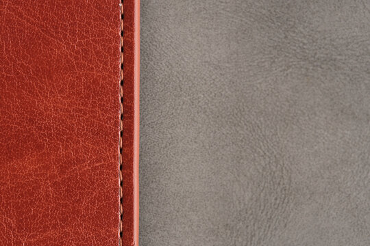 High contrast background showing brown stitched leather seam meeting smooth grey suede surface.