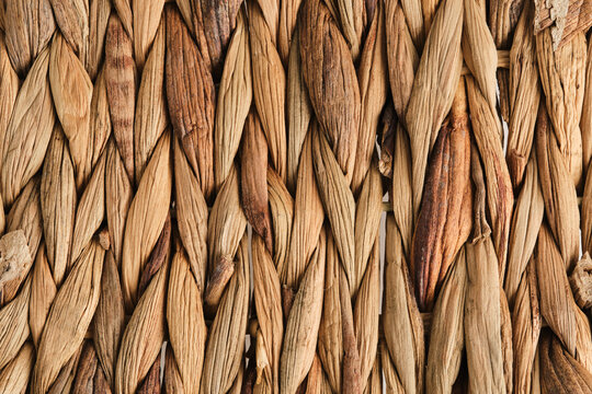 Macro background texture vertically woven natural dried straw or water hyacinth fibers in warm brown.