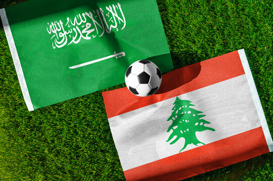 Saudi Arabia vs. Lebanon football match. National flags on green grass with soccer ball in the middle. Football background for international match.