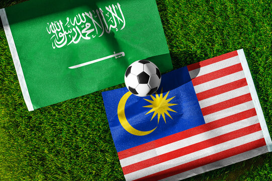 Saudi Arabia vs. Malaysia football match. National flags on green grass with soccer ball in the middle. Football background for international match.