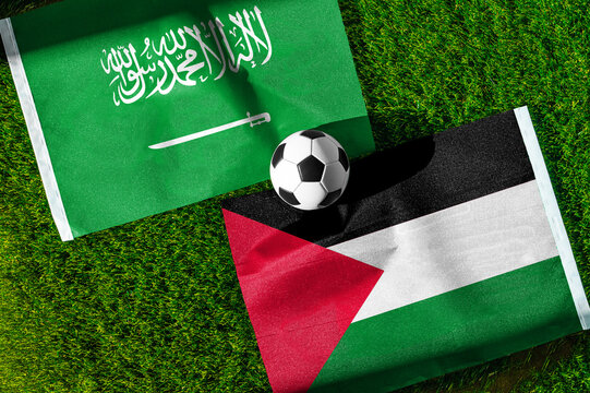 Saudi Arabia vs. Palestine football match. National flags on green grass with soccer ball in the middle. Football background for international match.