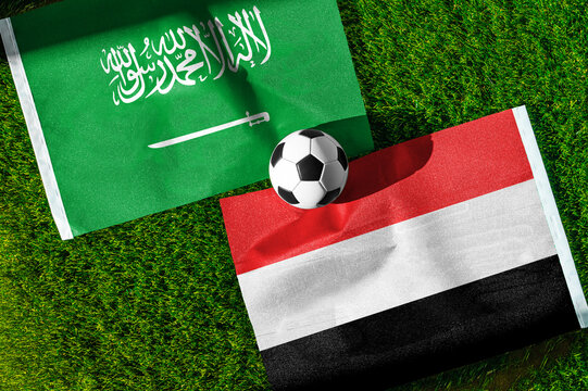 Saudi Arabia vs. Yemen football match. National flags on green grass with soccer ball in the middle. Football background for international match.