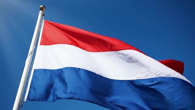 Flag of the netherlands waving against a clear blue sky