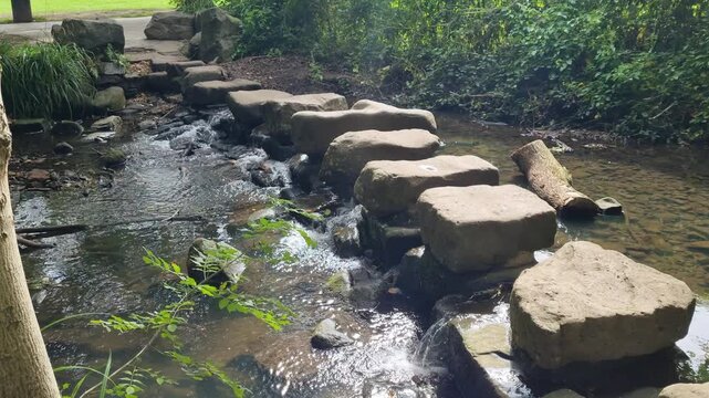 Clear stream flowing over a stone path crossing the water in a natural park