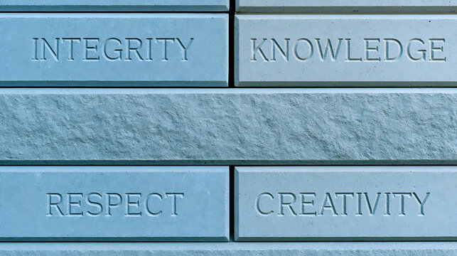 Stone wall blocks carved with core business values integrity, knowledge, respect, and creativity as corporate ethics and leadership concept