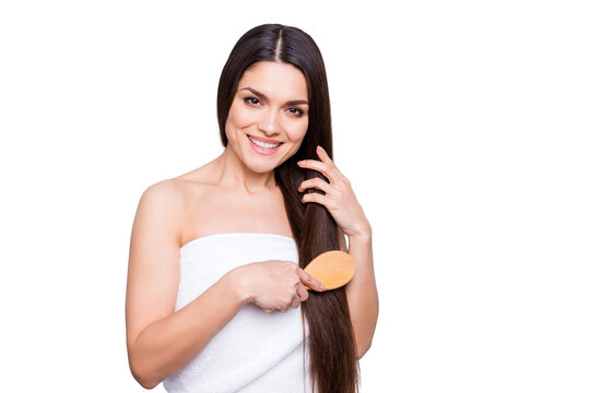 Portrait of pretty brunette woman with long strong hair combing with brush wrapped in white towel isolated on grey background. Dry ends oiled damage minerals haircut therapy effect concept