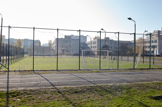 School Football Field with Green Artificial Turf Behind Metal Mesh Fence