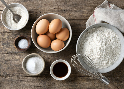 Baking ingredients flat lay with eggs flour and whisk on a rustic wooden table vector style