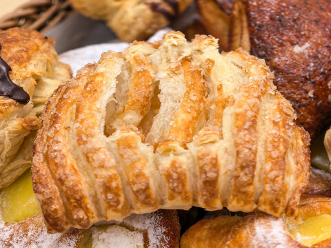 Close-up of crisp golden puff pastry with sugar crystals on top, bakery background. 