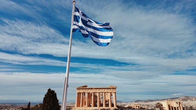 The Greek national flag waving in the wind with the ancient Parthenon temple in the background, Athens, Greece