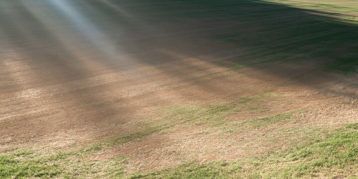 Empty threshing yard with warm sunlight streaming across a smooth clay surface, featuring earthy tones and copy space for a seasonal background