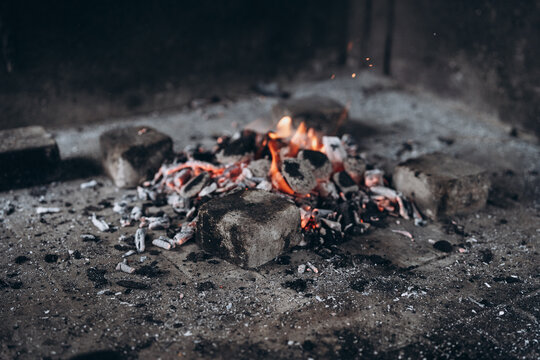 Glowing campfire coals and small flames in a stone fire pit