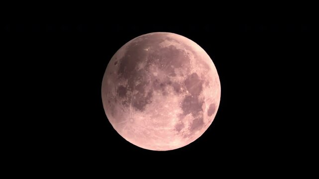 Timelapse of a red blood moon during a lunar eclipse as night turns into day, with the moon remaining visible against a bright blue sky
