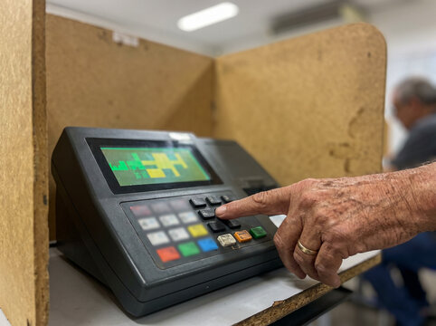 Senior voter using an electronic voting machine in a polling booth during an election