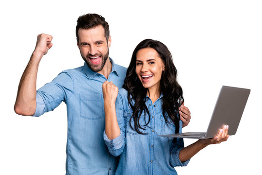 Portrait of joyful delighted students fellowship isolated impressed by victory luck aims raising fists holding hand pc shouting yeah dressed in beautiful denim shirts on argent background