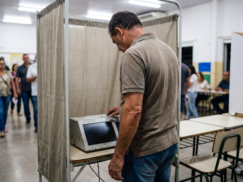 Middle-aged man casting his ballot on an electronic voting machine inside a polling booth during an election