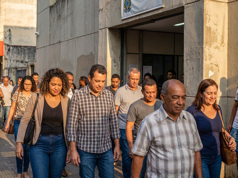 Group of diverse Latin American people walking out of a public building on a sunny day in the city