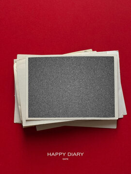 Stack of vintage paper envelopes and blank dark textured card mockup on vibrant red background, top view flat lay stationery layout with copy space